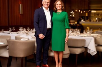 Elegantní pár ve středním věku u slavnostně prostřeného stolu v luxusní restauraci.